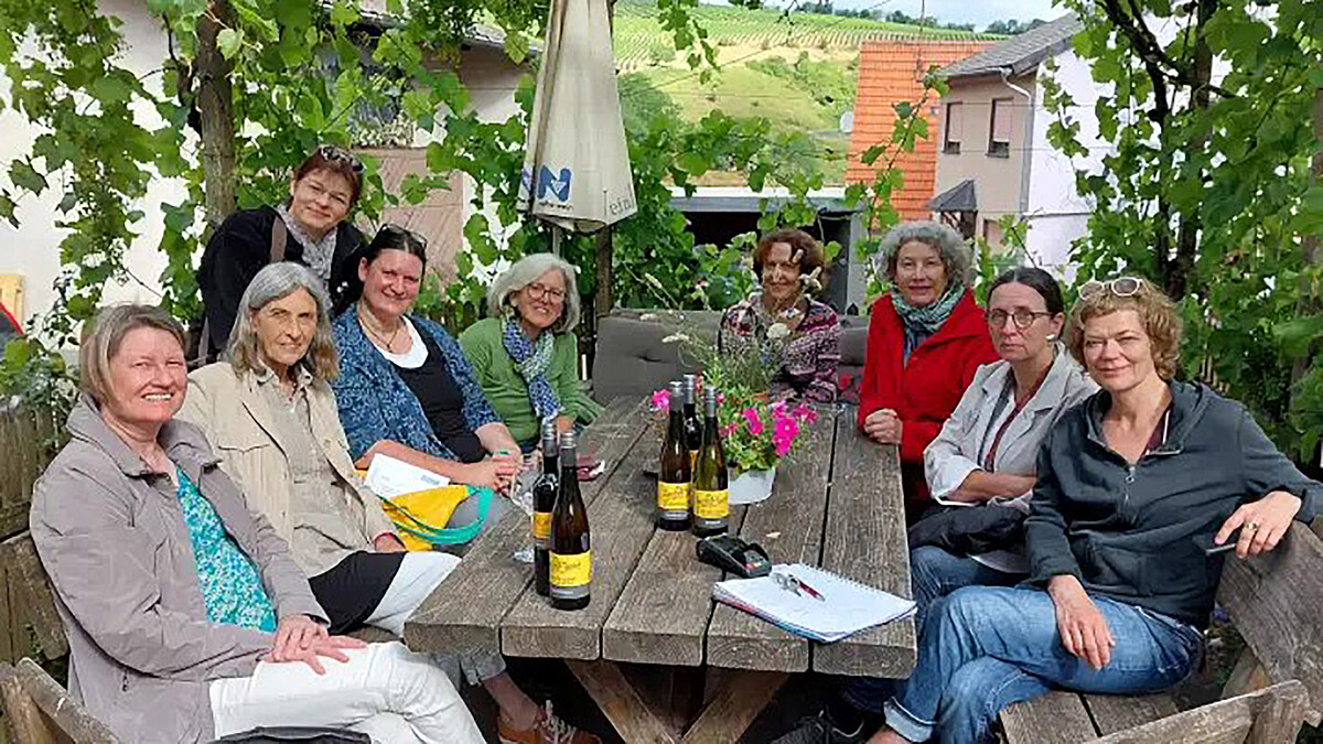 Eine Frauengruppe sitzt draußen an einem Holztisch während der Netzwerkstatt in Schlossböckelheim.